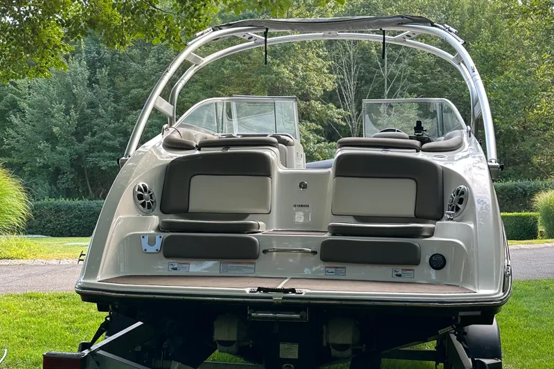 Slide: The Image of 2012 Yamaha Boats 242 Limited S on trailer, rear view in lush green setting. - 15