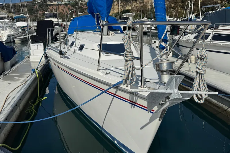 Slide: The Image of 1994 Catalina 320 sailboat docked in marina, featuring blue sail covers and anchor. - 10