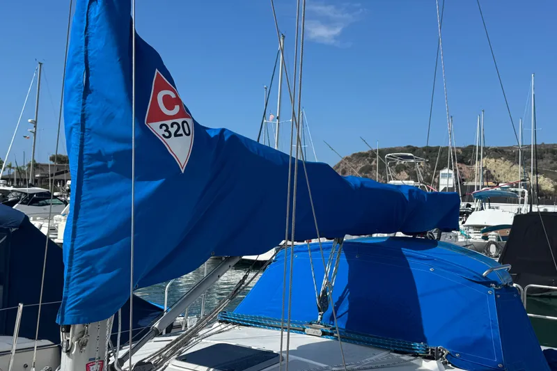 Slide: The Image of 1994 Catalina 320 sailboat with blue sail cover docked in marina. - 13