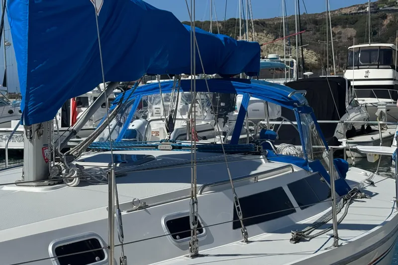 Slide: The Image of 1994 Catalina 320 sailboat with blue covers docked in a marina. - 2