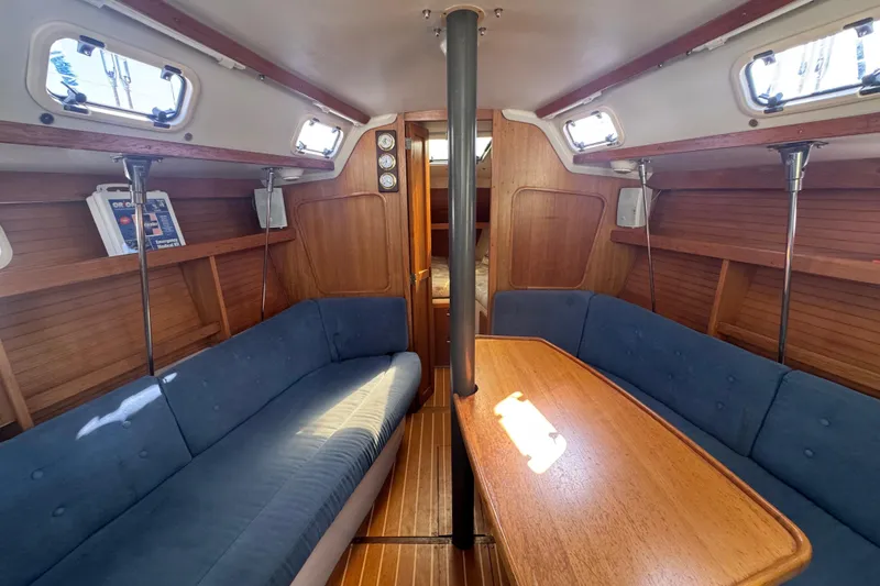 Slide: The Image of Interior of a 1994 Catalina 320 sailboat with blue seating and wooden table. - 26