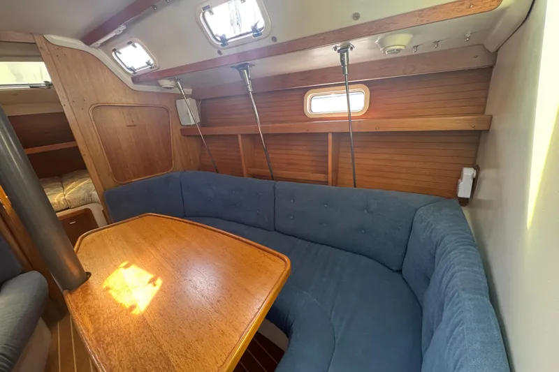Slide: The Image of Interior of 1994 Catalina 320 sailboat with blue cushioned seating and wooden table. - 28