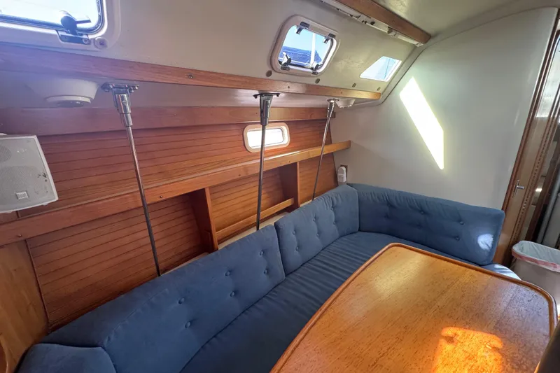 Slide: The Image of Interior of a 1994 Catalina 320 sailboat with blue cushioned seating and wooden table. - 31