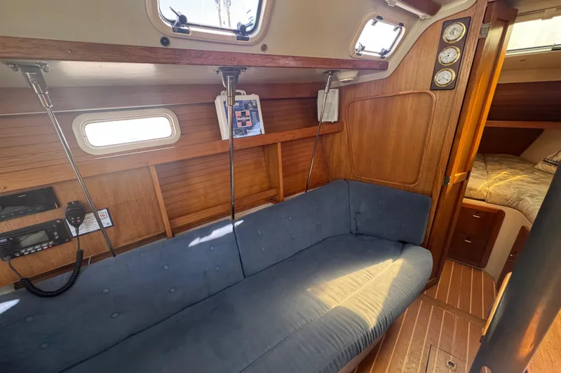 Slide: The Image of Cozy interior of a 1994 Catalina 320 sailboat with blue seating and wooden accents. - 32