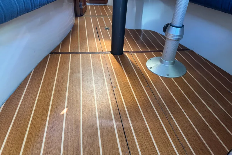 Slide: The Image of 1994 Catalina 320 interior with polished wooden flooring and metal support poles. - 33