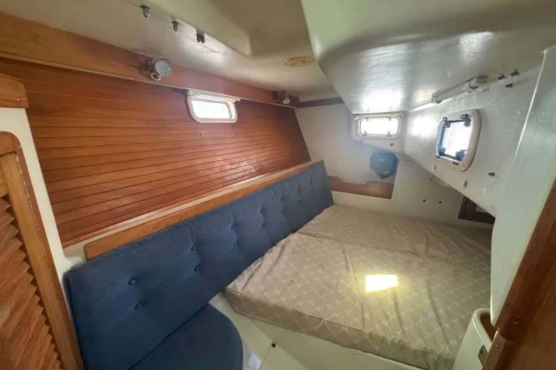 Slide: The Image of Cozy cabin interior of 1994 Catalina 320 sailboat with wooden accents and blue seating. - 36