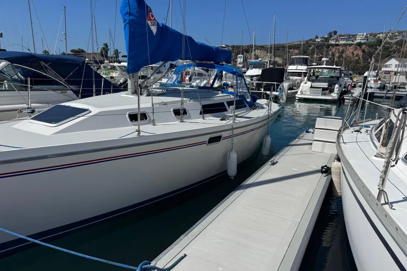 Slide: The Image of 1994 Catalina 320 sailboat docked in a marina, surrounded by other boats. - 4