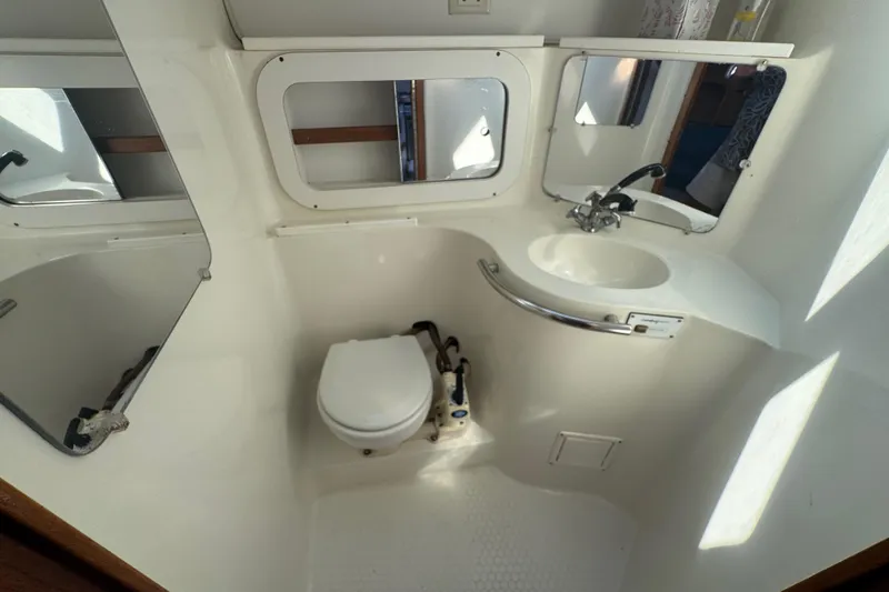 Slide: The Image of Bathroom interior of a 1994 Catalina 320 sailboat, featuring a compact toilet and sink. - 43