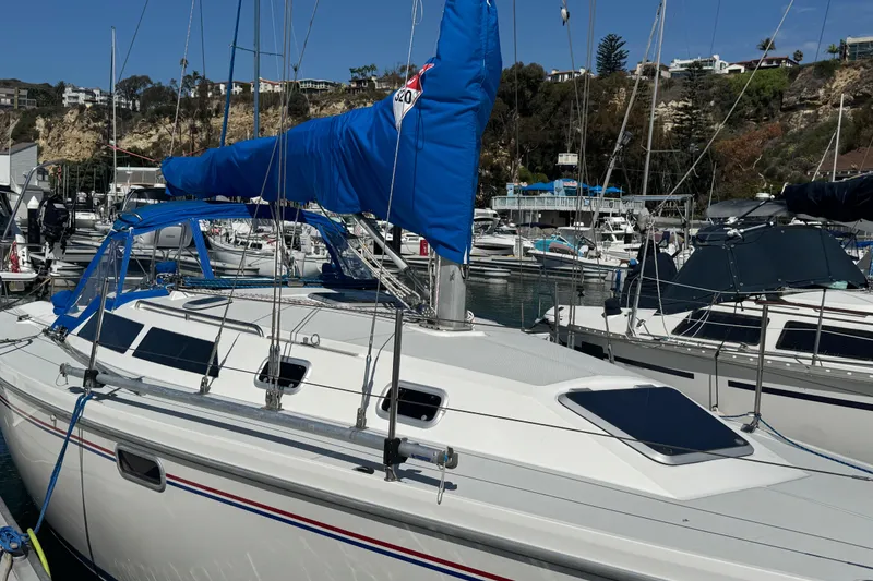 Slide: The Image of Sailboat Catalina 320, 1994 model, docked in a marina with blue sail cover. - 5