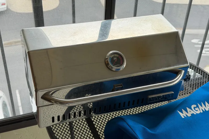 Slide: The Image of Stainless steel Magma grill on a patio table, with a blue cover nearby. - 54