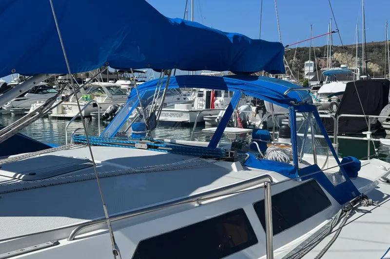 Slide: The Image of 1994 Catalina 320 sailboat docked in marina, featuring blue canopy and sleek design. - 6