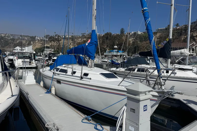 Slide: The Image of 1994 Catalina 320 sailboat docked in a marina, surrounded by other boats. - 9