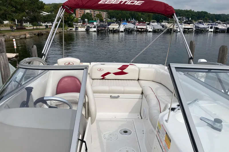Slide: The Image of 2005 Ebbtide 2400 Fun Cruiser DC boat interior at marina, featuring white seating and red accents. - 10