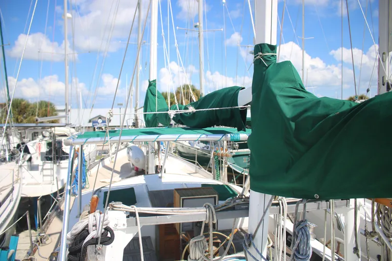 Slide: The Image of 1981 Hardin 45 Voyager sailboat with green covers docked at marina under blue sky. - 8