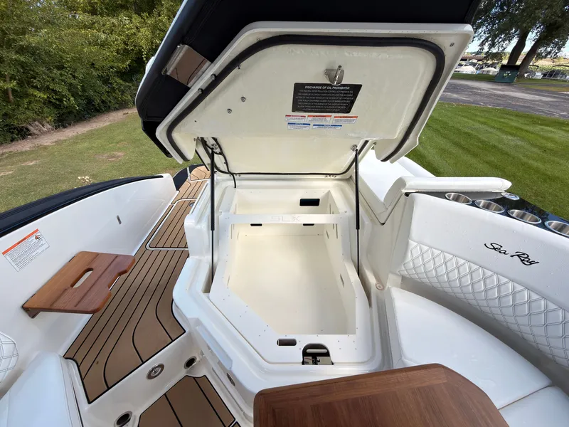 Slide: The Image of The image shows the storage area of a 2026 Sea Ray SLX 280 Outboard boat. The space is clean and spacious, featuring wood accents and cushioned seating. - 39