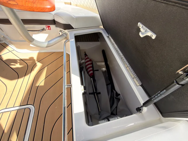 Slide: The Image of An open storage compartment on a Sea Ray SLX 280 Outboard boat reveals a flag and other items. - 45