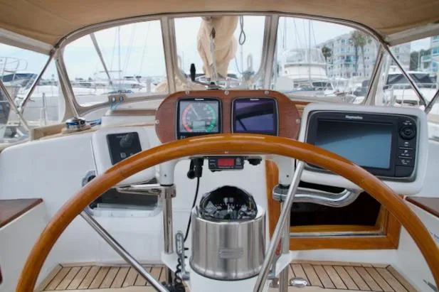 Slide: The Image of Cockpit view of a 1986 Passport 42 sailboat with navigation instruments and wooden steering wheel. - 12