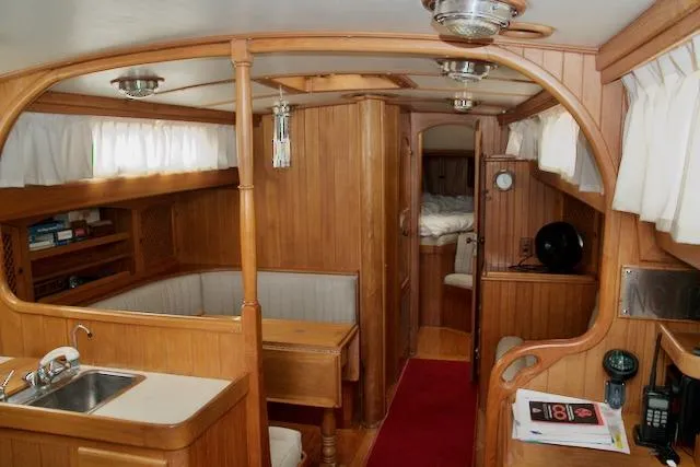 Slide: The Image of Interior of 1986 Passport 42 sailboat with wooden furnishings and cozy seating area. - 14