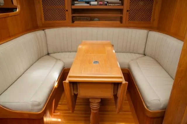 Slide: The Image of Cozy wooden interior of 1986 Passport 42 yacht with cushioned seating and table. - 25