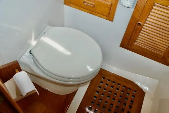 Slide: The Image of 1986 Passport 42 yacht bathroom with wooden accents and white toilet. - 28