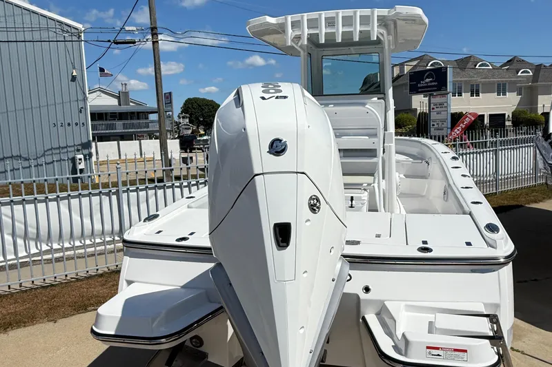 Slide: The Image of 2026 Blackfin 242 HB boat with powerful outboard motor, docked under clear blue sky. - 2