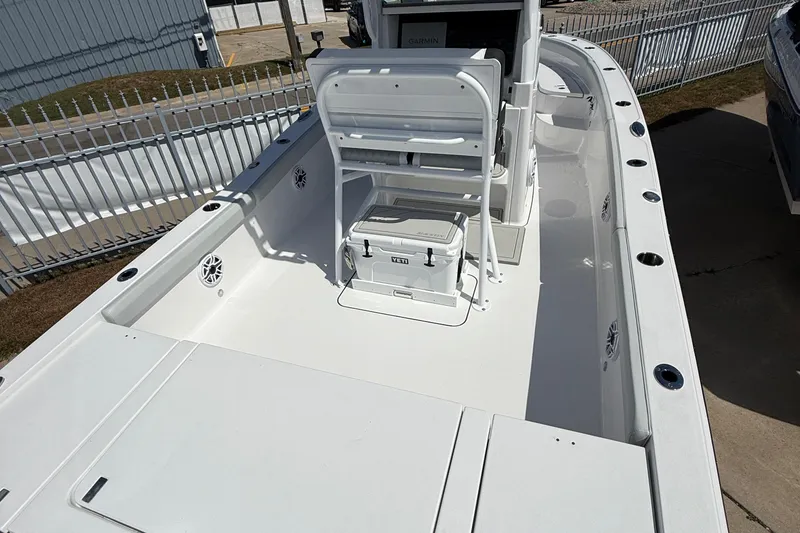 Slide: The Image of 2026 Blackfin 242 HB boat interior with seating and cooler, docked near a fence. - 6