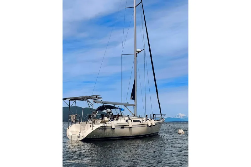 Slide: The Image of 2003 Catalina 42 MkII sailboat anchored on calm water under a clear blue sky. - 2