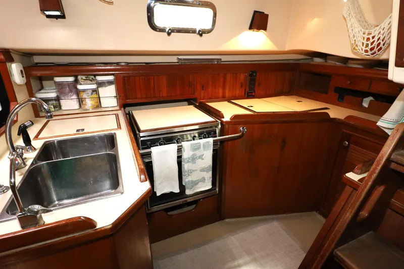 Slide: The Image of Interior of 1995 Island Packet 40 sailboat kitchen with sink, stove, and wooden cabinetry. - 13