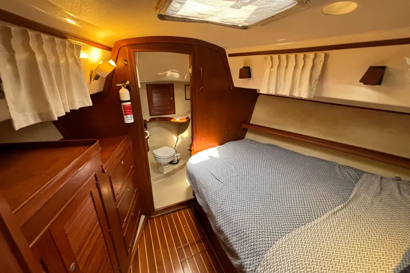 Slide: The Image of 1995 Island Packet 40 yacht cabin with bed, wooden interior, and adjacent bathroom. - 19