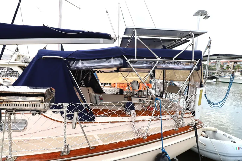 Slide: The Image of 1995 Island Packet 40 sailboat docked, featuring blue canopy and solar panels. - 65