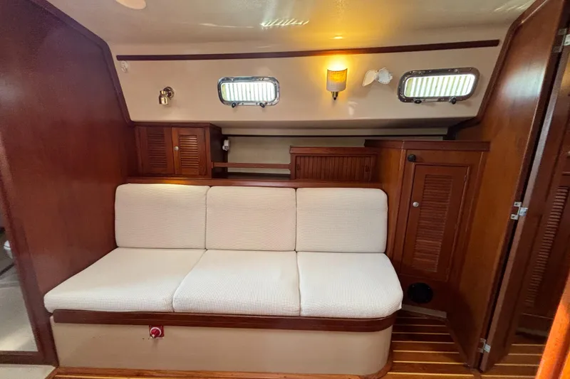 Slide: The Image of Interior of 1995 Island Packet 40 sailboat with cushioned seating and wooden cabinetry. - 7