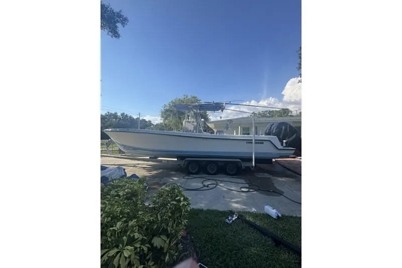 The Image of 2005 Contender 31 Open boat on trailer, parked outdoors under clear blue sky. - 1