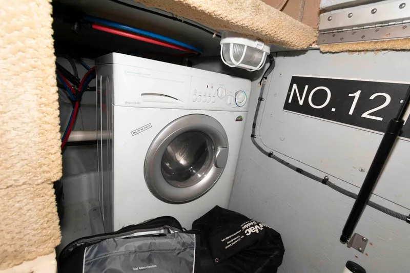 Slide: The Image of Laundry area inside 2007 Meridian 459 Motoryacht, featuring a washing machine and storage. - 22
