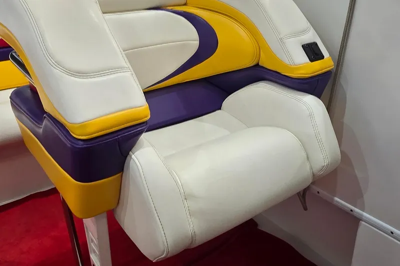 Slide: The Image of 1997 Baja 322 boat seat with white, yellow, and purple upholstery on red carpet. - 10