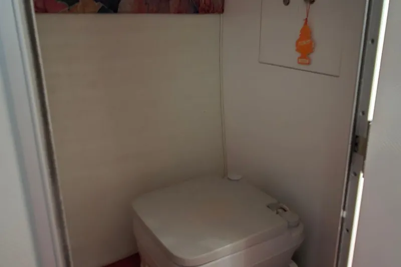 Slide: The Image of Compact bathroom in a 1997 Baja 322 boat, featuring a portable toilet. - 14