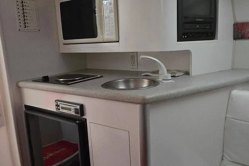 Slide: The Image of 1997 Baja 322 boat interior with kitchenette, featuring microwave, sink, and stove. - 15