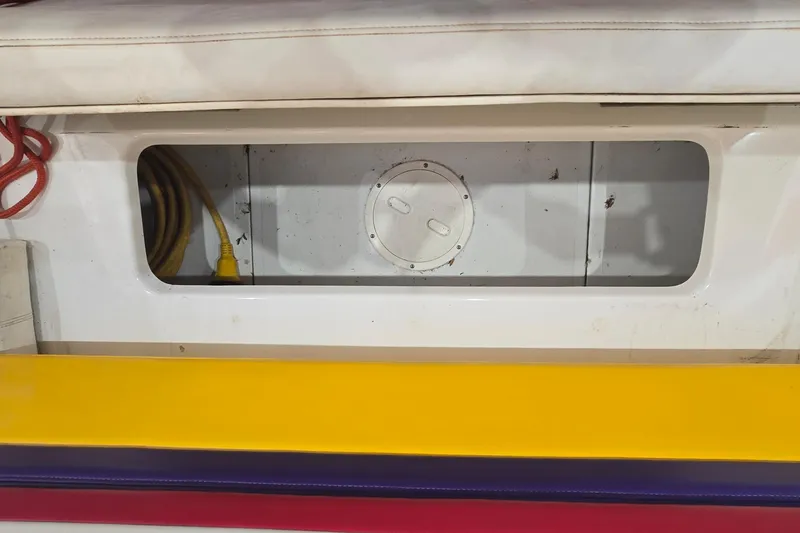 Slide: The Image of Storage compartment of a 1997 Baja 322 boat with colorful seating and visible wiring. - 21