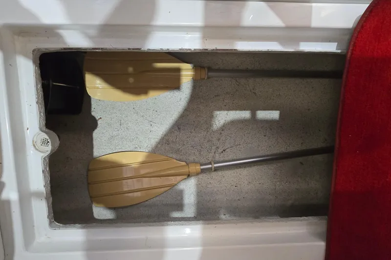 Slide: The Image of Storage compartment with two beige paddles in a 1997 Baja 322 boat. - 23