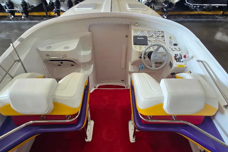 Slide: The Image of 1997 Baja 322 boat cockpit with white and yellow seats, red carpet, and control panel. - 6