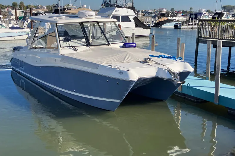 Slide: The Image of 2021 World Cat 320 DC boat docked in a marina, featuring a sleek blue and white design. - 3