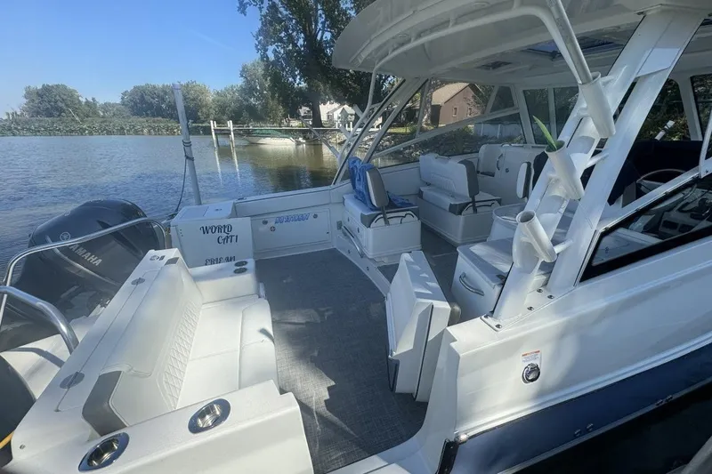 Slide: The Image of 2021 World Cat 320 DC boat interior with seating, docked by a serene lake. - 6