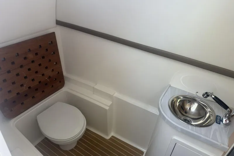 Slide: The Image of 2021 World Cat 320 DC boat bathroom with toilet and sink, featuring wood accents. - 28