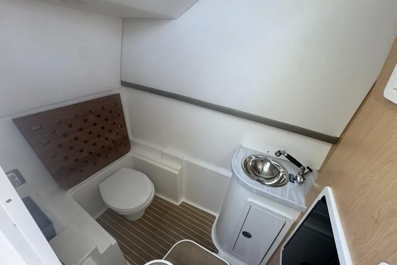 Slide: The Image of 2021 World Cat 320 DC boat interior bathroom with toilet, sink, and wooden flooring. - 29