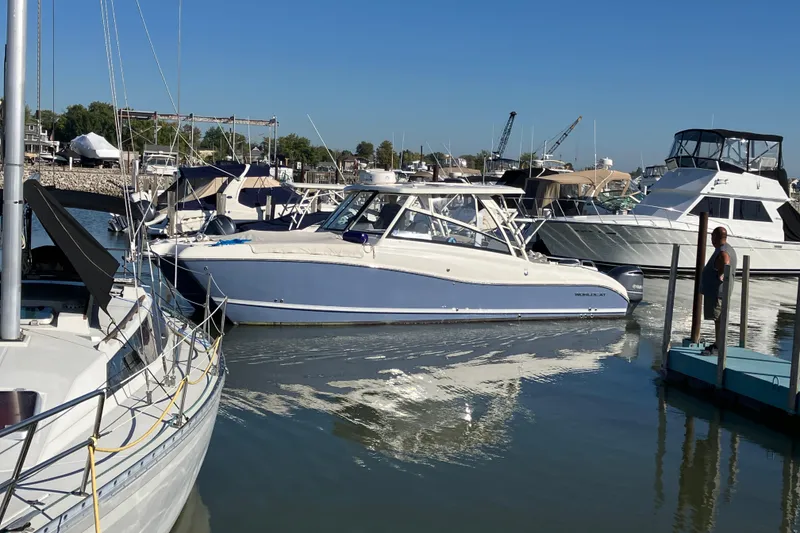 Slide: The Image of 2021 World Cat 320 DC boat docked in a marina, surrounded by other vessels. - 30