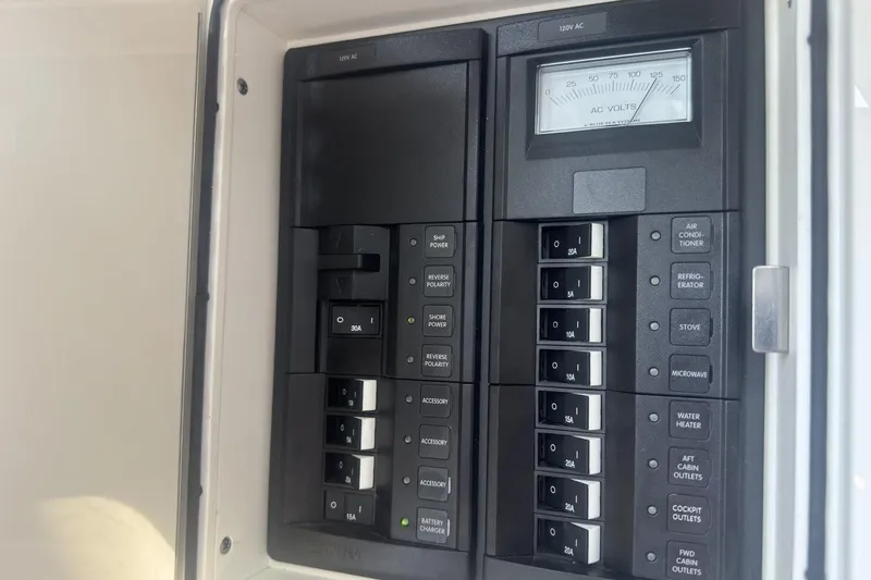 Slide: The Image of Electrical panel on a 2021 World Cat 320 DC boat, featuring circuit breakers and voltage meter. - 25