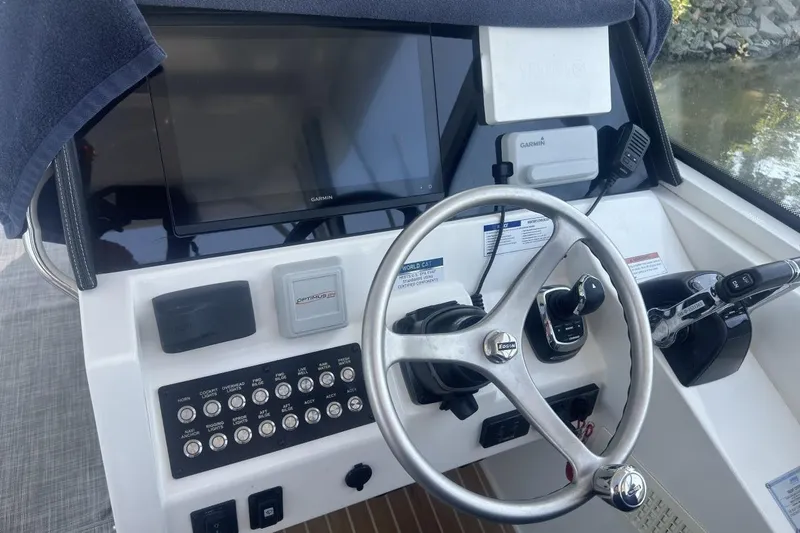 Slide: The Image of Helm of 2021 World Cat 320 DC boat with steering wheel and control panel. - 16