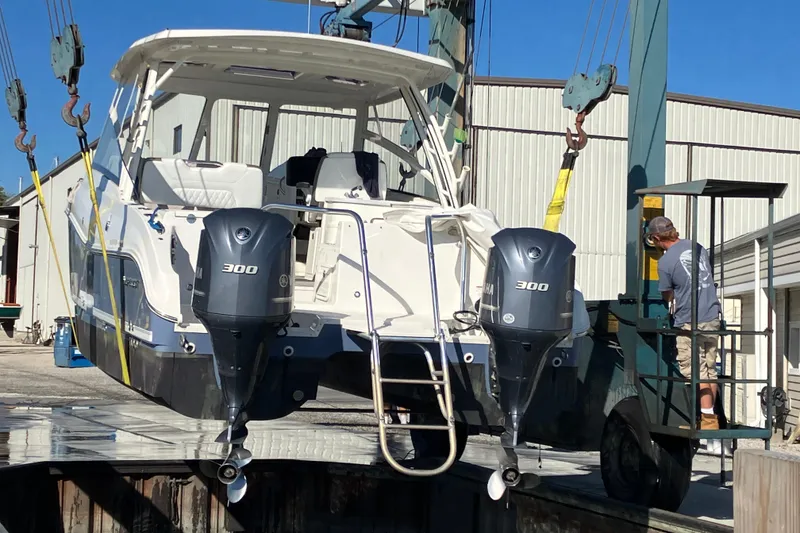 Slide: The Image of 2021 World Cat 320 DC boat being lifted by a crane at a marina. - 36