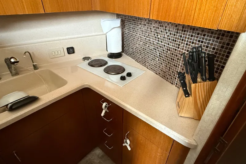 Slide: The Image of Compact kitchen in 1999 Ocean Yachts 40 Express, featuring stove, sink, and knife set. - 10