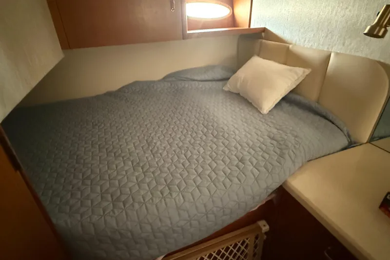 Slide: The Image of Cozy cabin bed in 1999 Ocean Yachts 40 Express, featuring a quilted blue cover. - 8