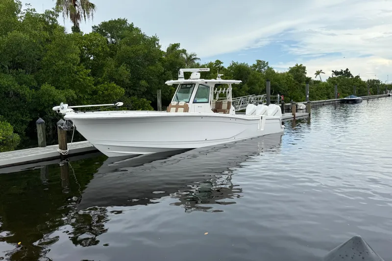 The Image of 2020 Caymas 341 CC boat docked on calm water, surrounded by lush greenery. - 0
